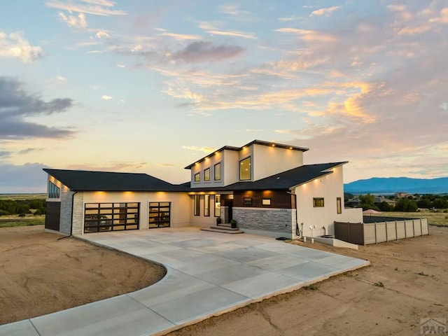 contemporary home with a garage, stone siding, driveway, and stucco siding