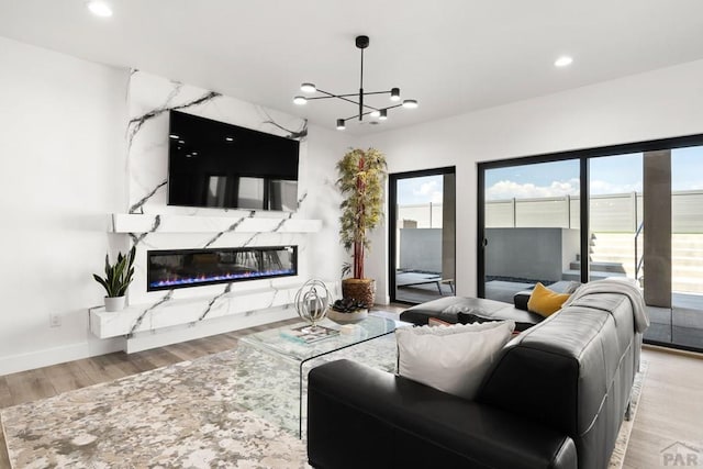 living room featuring baseboards, recessed lighting, a fireplace, an inviting chandelier, and wood finished floors