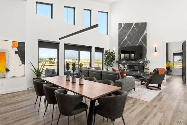 dining room featuring baseboards, wood finished floors, and a high end fireplace