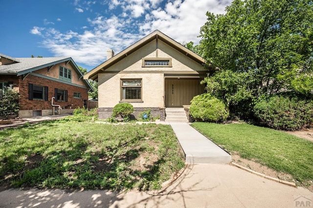 2325 W St, Pueblo, CO 81003 - view of front of property featuring brick siding, a front lawn, and a chimney