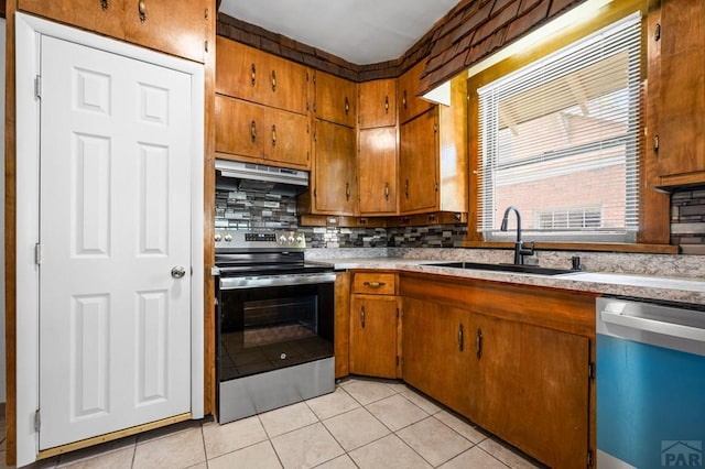 2325 W St, Pueblo, CO 81003 - kitchen with stainless steel electric range, dishwashing machine, under cabinet range hood, light tile patterned flooring, and backsplash