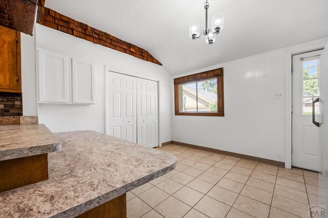2325 W St, Pueblo, CO 81003 - kitchen with lofted ceiling, a chandelier, decorative backsplash, light countertops, and light tile patterned floors