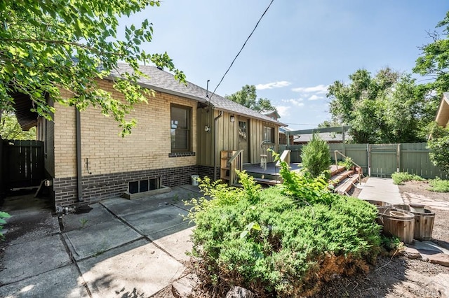 2325 W St, Pueblo, CO 81003 - back of property with a wooden deck, brick siding, a fenced backyard, and a patio