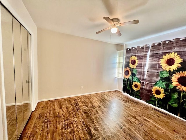 unfurnished bedroom with baseboards, wood finished floors, and a ceiling fan