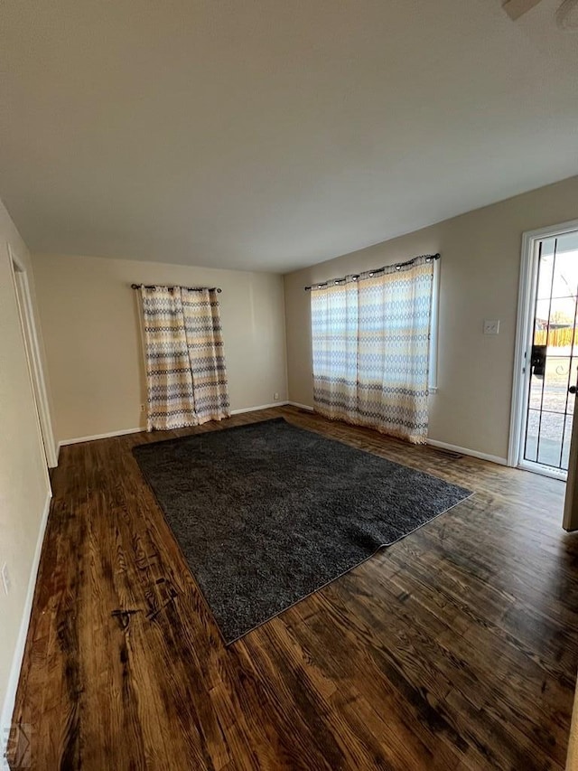 unfurnished living room with wood finished floors and baseboards