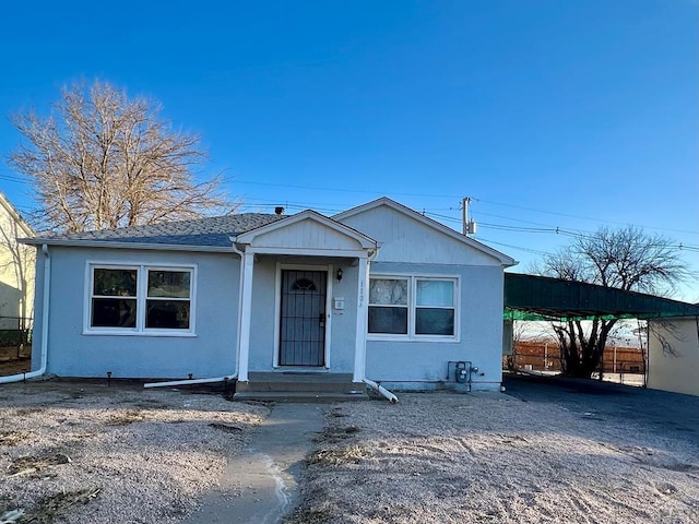 view of front of home featuring a carport, stucco siding, and fence