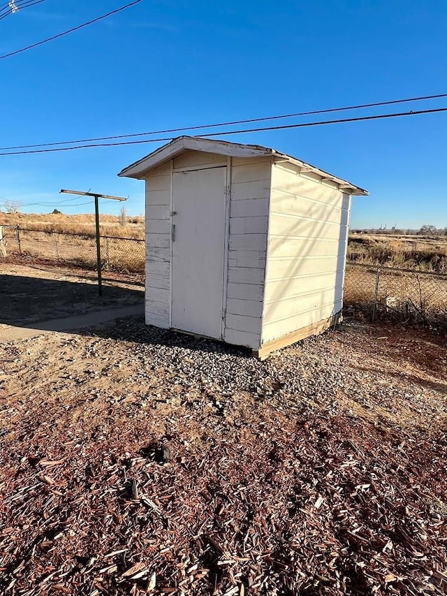 view of shed featuring a rural view and fence