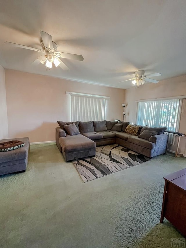 living area featuring ceiling fan, baseboards, and light colored carpet