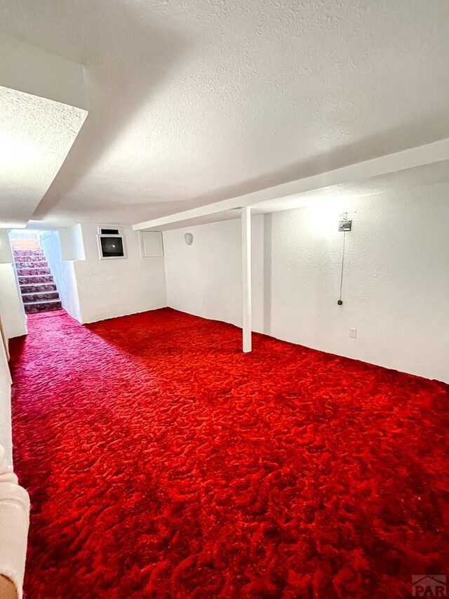 finished basement with stairs, a textured ceiling, and carpet flooring