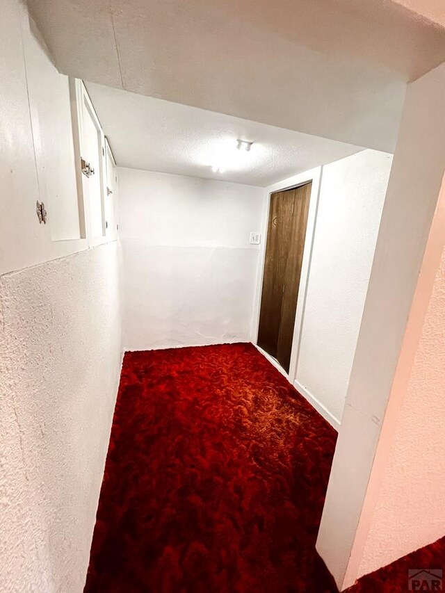 hallway featuring carpet and a textured ceiling