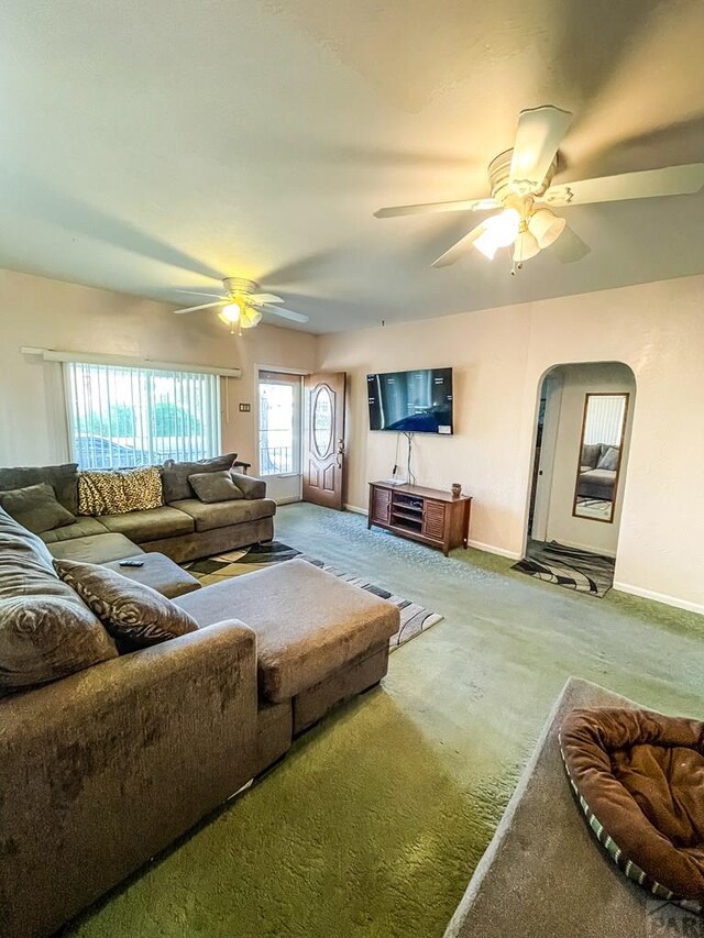 living area featuring carpet, ceiling fan, arched walkways, and baseboards