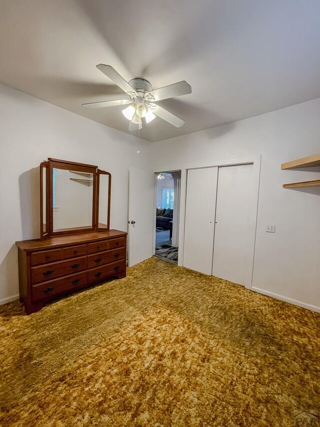 unfurnished bedroom with carpet floors, a ceiling fan, and a closet