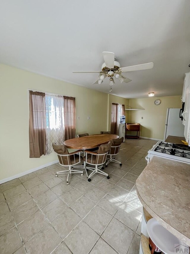 dining area with a ceiling fan, baseboards, and light tile patterned floors