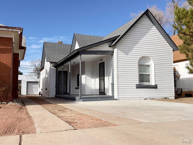1127 E Orman Ave, Pueblo, CO 81004 - bungalow-style home with a porch, a garage, roof with shingles, and an outbuilding