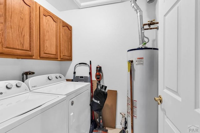 washroom with washing machine and clothes dryer, water heater, and cabinet space