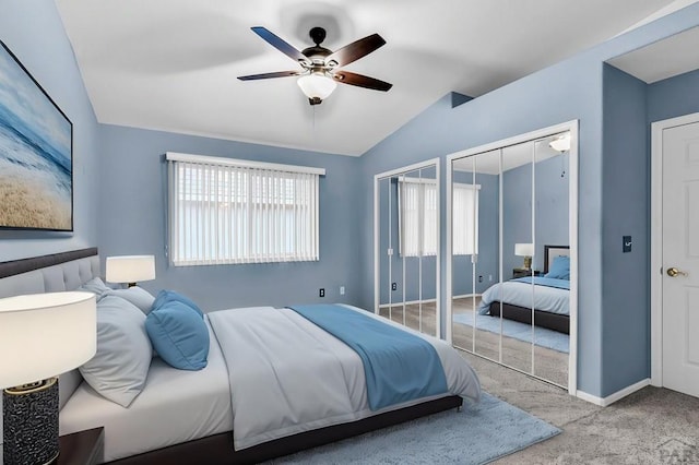 bedroom featuring lofted ceiling, a ceiling fan, baseboards, two closets, and carpet floors