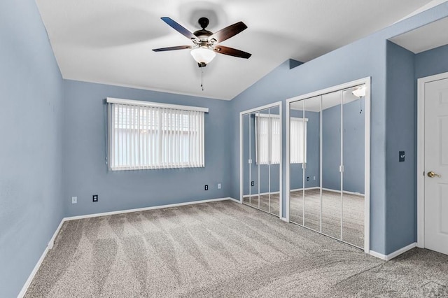 unfurnished bedroom with baseboards, multiple closets, carpet, and vaulted ceiling
