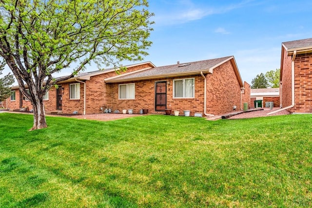 back of property with a yard and brick siding