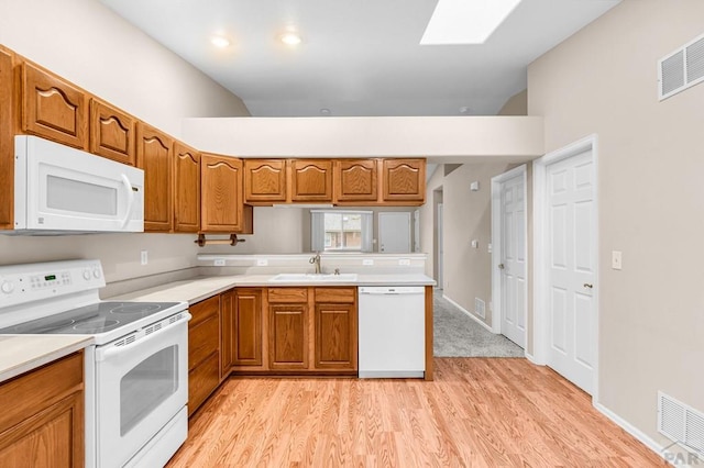 kitchen with a sink, white appliances, visible vents, and brown cabinets