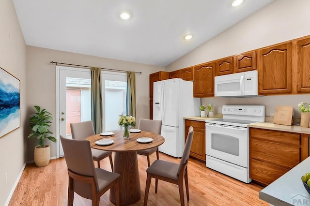 kitchen featuring vaulted ceiling, light wood finished floors, brown cabinetry, and white appliances