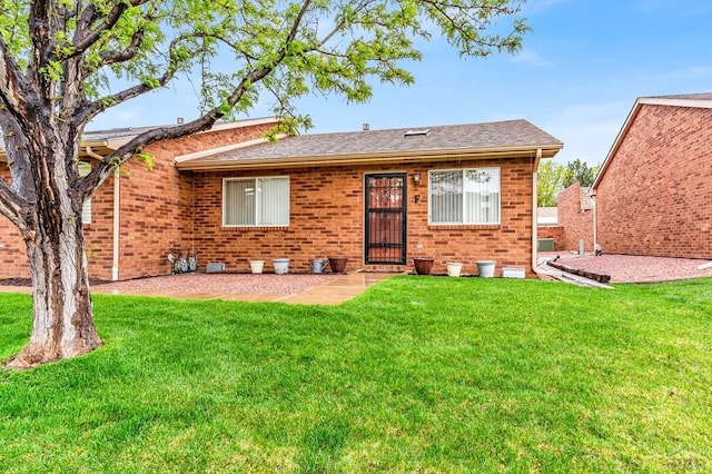 view of front of house featuring brick siding, roof with shingles, and a front yard