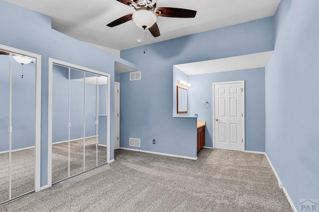unfurnished bedroom featuring visible vents, two closets, and carpet