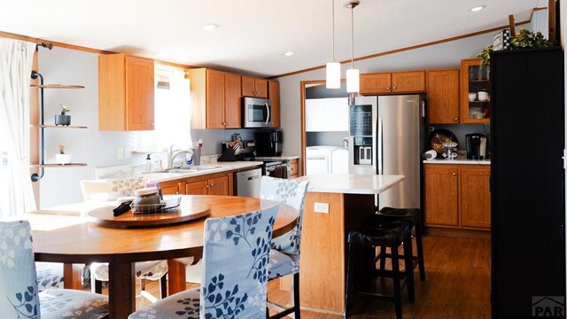 kitchen featuring decorative light fixtures, washing machine and clothes dryer, light countertops, appliances with stainless steel finishes, and a sink