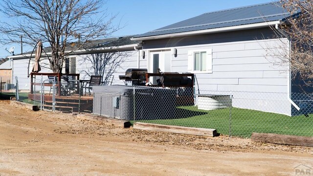 rear view of house featuring fence and metal roof