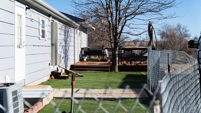 view of yard with ac unit, fence, and a wooden deck