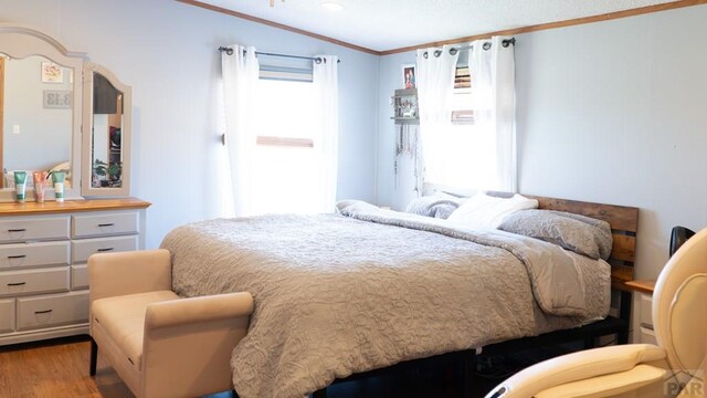 bedroom with light wood finished floors and crown molding