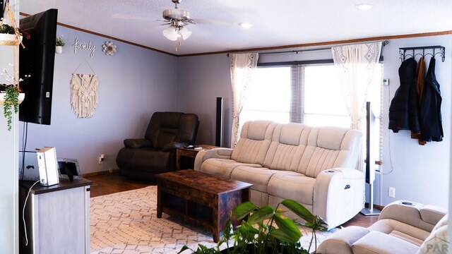 living room featuring ceiling fan, ornamental molding, wood finished floors, and baseboards