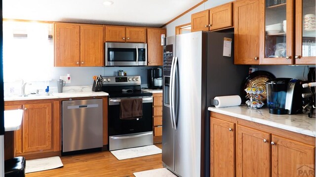 kitchen with glass insert cabinets, appliances with stainless steel finishes, and brown cabinetry