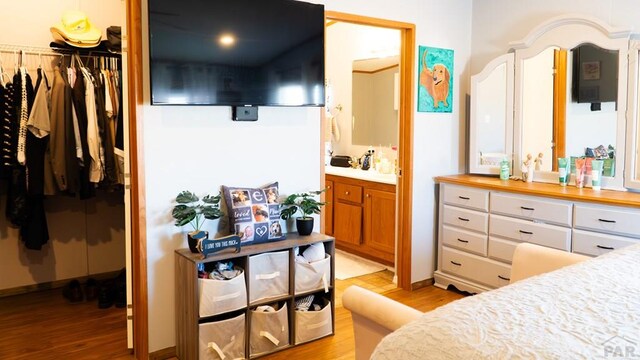 bedroom featuring a closet, a spacious closet, light wood finished floors, and ensuite bathroom