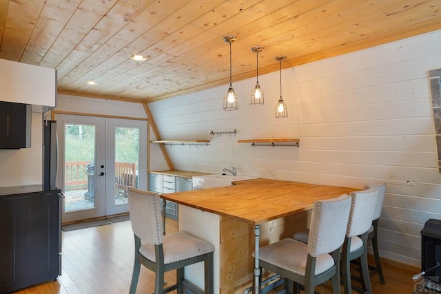 dining space with wooden walls, french doors, wood ceiling, and light wood-style floors