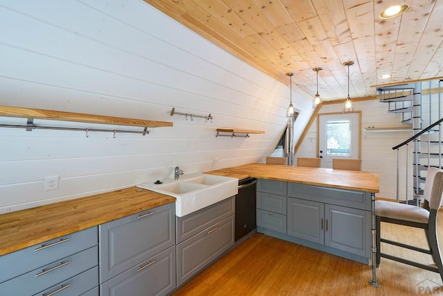 kitchen featuring a sink, open shelves, butcher block counters, and hanging light fixtures