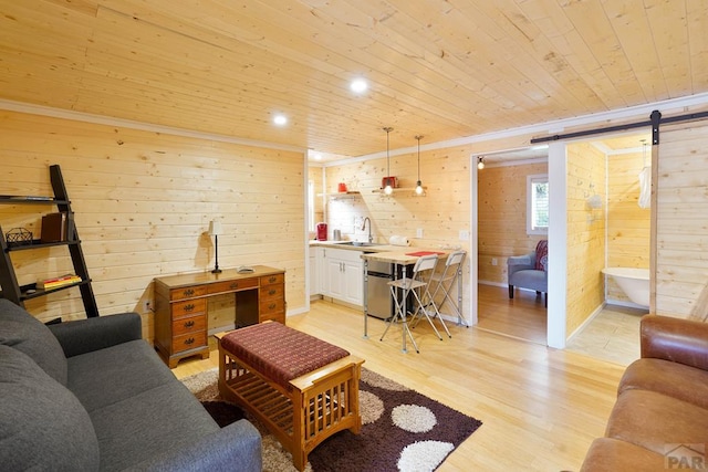 living room with a barn door, wooden ceiling, wood walls, light wood-style floors, and ornamental molding