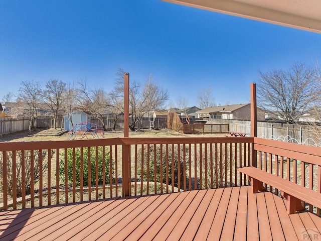 wooden deck featuring an outbuilding, a storage unit, a fenced backyard, and a residential view