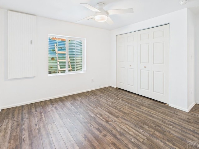 unfurnished bedroom with ceiling fan, wood finished floors, a closet, and baseboards