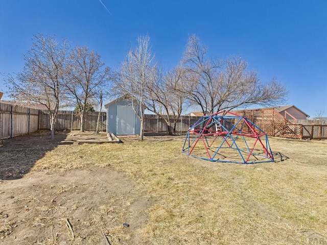 view of yard with an outbuilding, a storage unit, a playground, and a fenced backyard