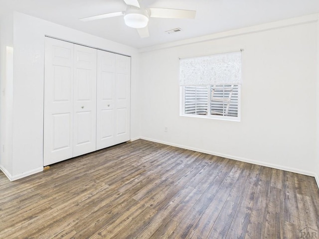 unfurnished bedroom featuring a closet, baseboards, visible vents, and wood finished floors