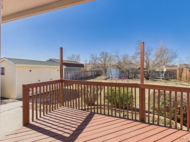 wooden terrace with a storage unit, a fenced backyard, a yard, and an outdoor structure