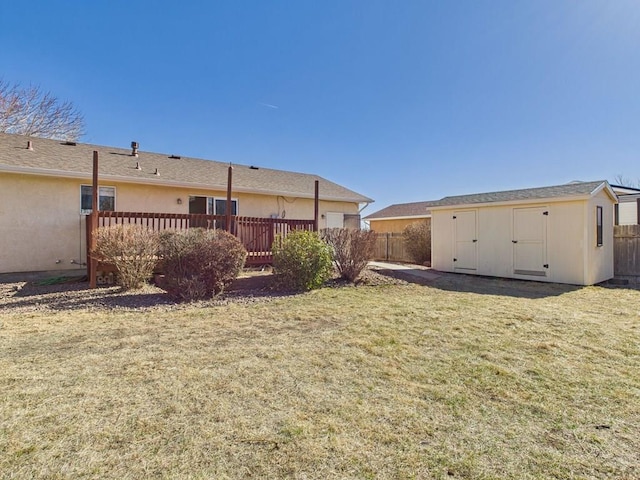 rear view of house with fence, stucco siding, a lawn, a storage shed, and an outdoor structure