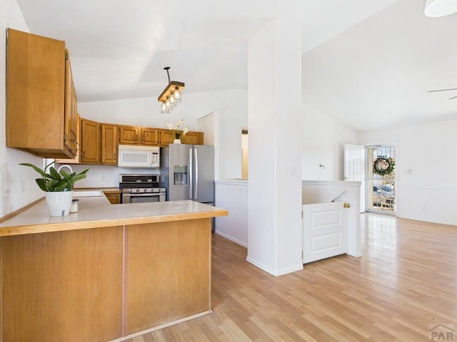 kitchen featuring light wood-type flooring, appliances with stainless steel finishes, a peninsula, brown cabinetry, and light countertops