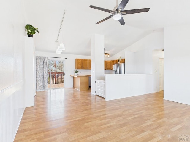 unfurnished living room featuring track lighting, light wood-style flooring, ceiling fan, and vaulted ceiling