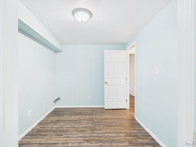 laundry room with a textured ceiling, baseboards, and wood finished floors