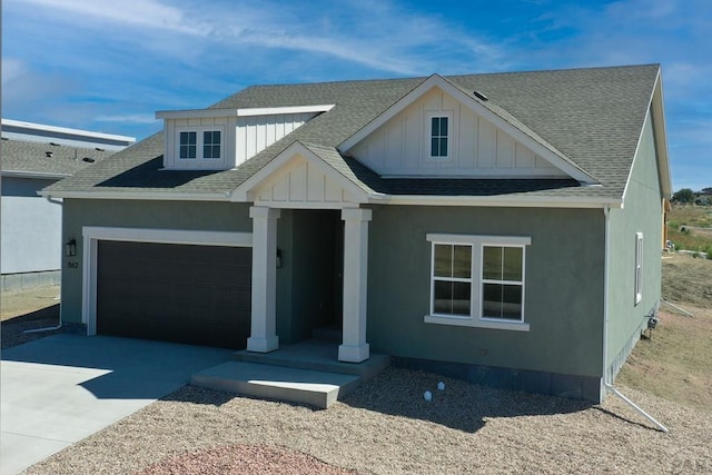 view of front facade featuring a garage, driveway, a shingled roof, and board and batten siding