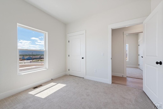 unfurnished bedroom with baseboards, visible vents, and light colored carpet