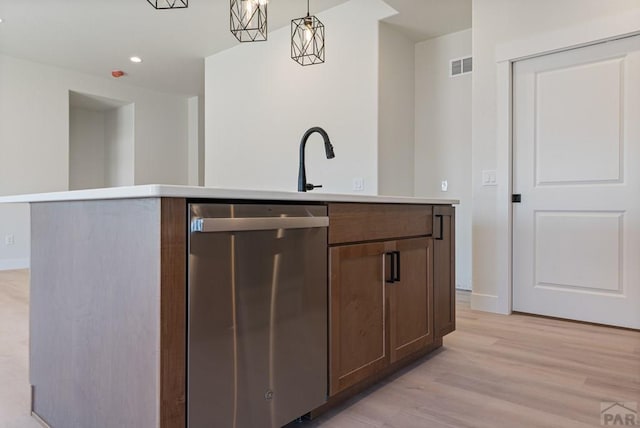 kitchen featuring a kitchen island with sink, visible vents, light countertops, and stainless steel dishwasher