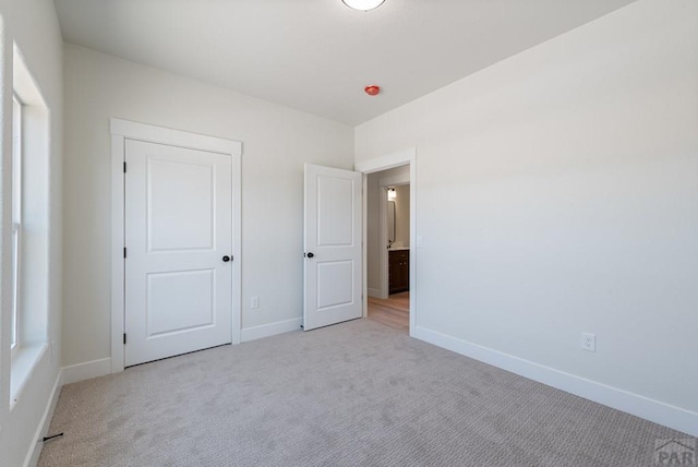 unfurnished bedroom featuring light carpet and baseboards