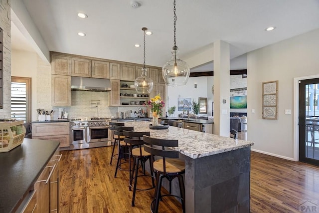 489 S Pin High Dr, Pueblo West, CO 81007 - kitchen featuring double oven range, under cabinet range hood, dark wood-style flooring, recessed lighting, and a breakfast bar area